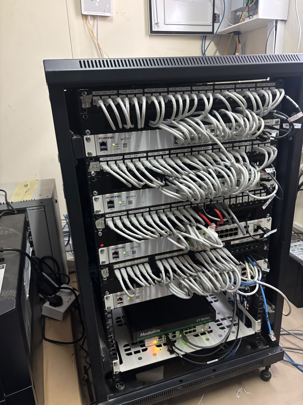 The reorganized network cabinet after the project, with Fortinet switches, labeled patch panels, and neatly dressed cables